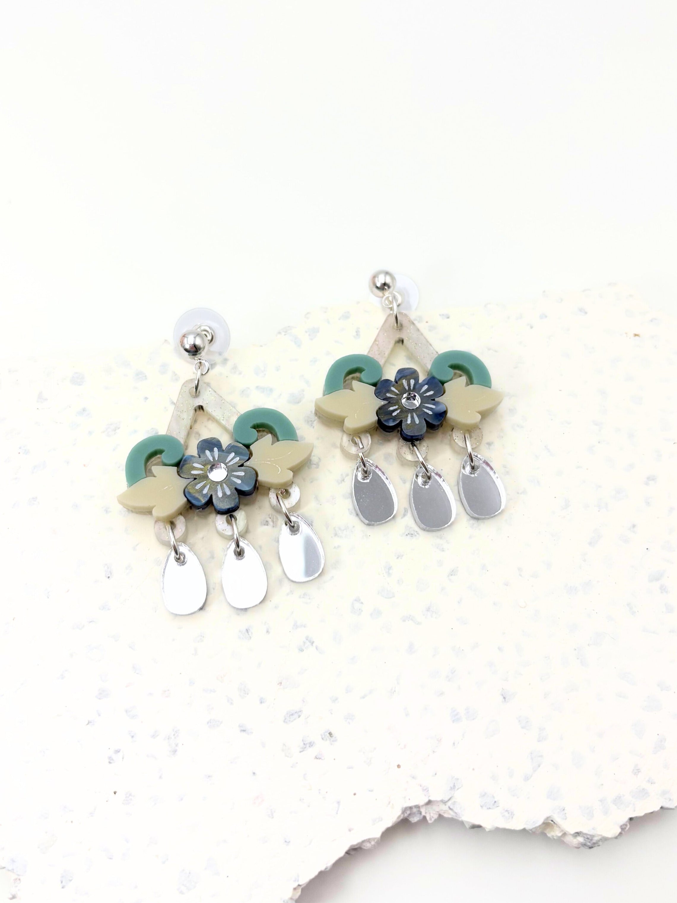 Pair of acrylic earrings with floral and teardrop designs on a white background